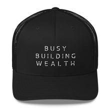 Load image into Gallery viewer, Black trucker cap that says Busy Building Wealth in white