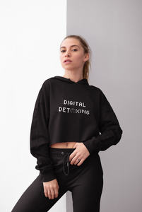 Woman wearing black crop top hoodie that says "Digital Detoxing"