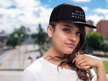 Load image into Gallery viewer, Woman wearing black trucker hat that says "Busy Building Wealth"