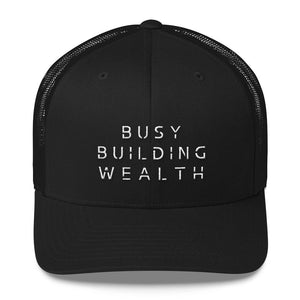 Black trucker cap that says Busy Building Wealth in white