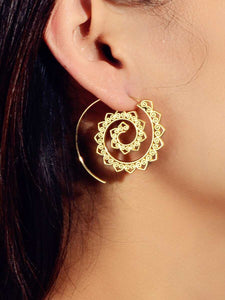Woman wearing gold spiral earrings with boho design