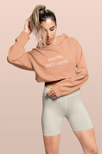 Woman wearing peach color crop top hoodie that says "Digital Detoxing"