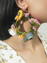 Load image into Gallery viewer, Woman wearing hoop earrings with multiple faux flowers attached to it