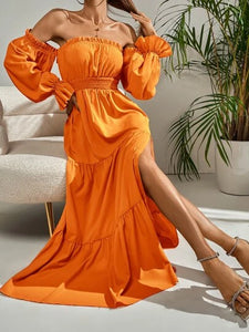 Woman wearing long orange flowy dress with sleeves 